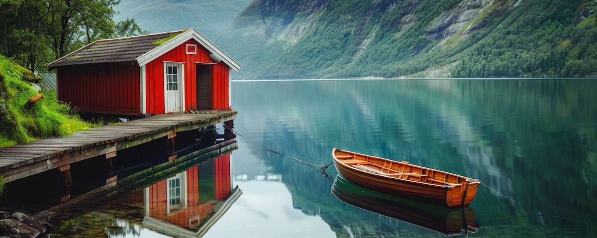 Rotes norwegisches Ferienhaus am Fjord mit Bootssteg und Boot