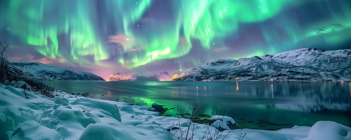 Grüne und violette Polarlichter über einem verschneiten Fjord in Norwegen