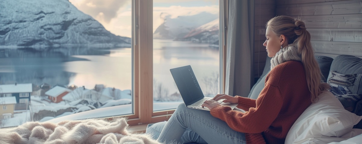 Frau lernt Norwegisch online am Laptop mit Fjordblick im Hintergrund